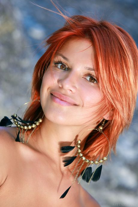 Young redhead Violla A models totally naked on a cliff in the sun
