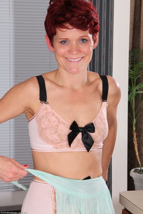 Redheaded mature Suzy Stanton toys with kitchen utensils in a solo