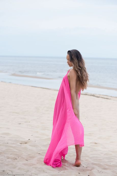 Endearing teen Slava A frees her tan lined body from pink wrap on a beach