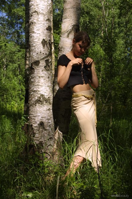 Lean teen with a beautiful face and a slim body poses naked in nature