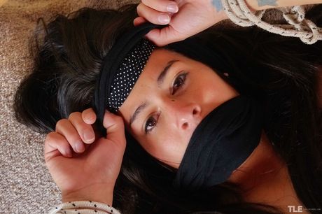 Tattooed girl Daisy B exhibits her big tits while being tied up on a bed