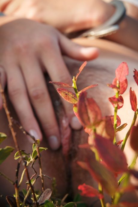 Blonde teen Kristine removes handcuffs and chains before masturbating in woods