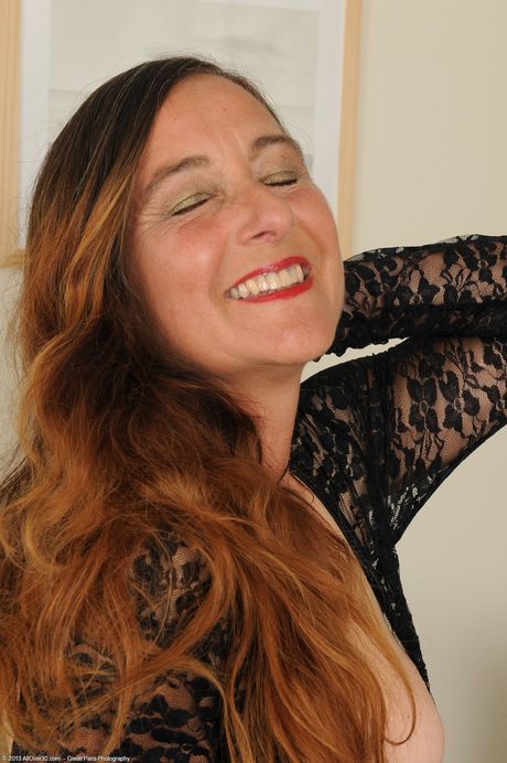 Mature redhead Nicola strips and rubs her bushy pussy in stockings