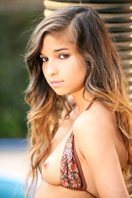 Teen model Nika removes her bikini to pose nude by a swimming pool