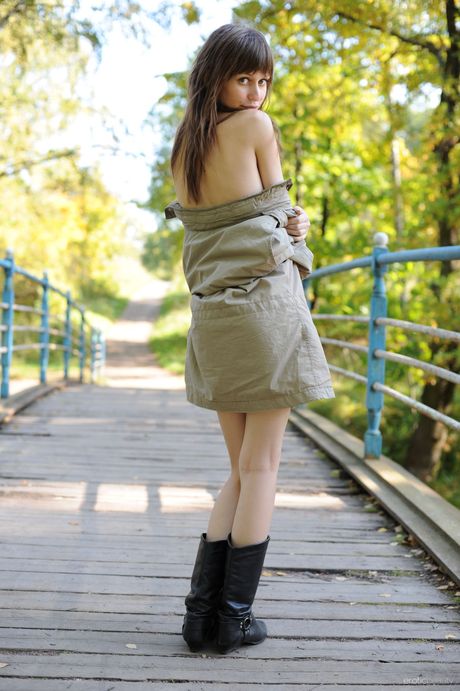 Svelte teen Lilly B poses nude in boots on a footbridge in a field