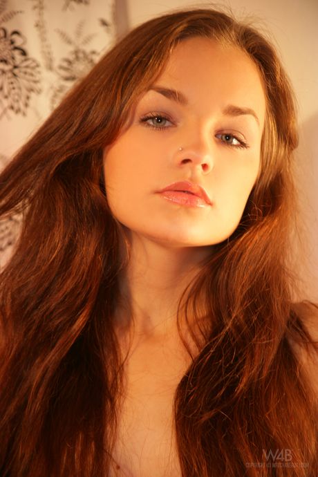 Cute teen Lily removes her stockings to get totally naked on a bed