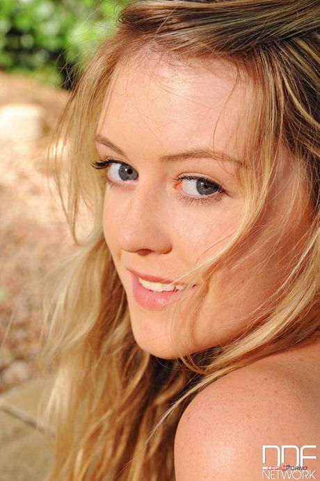 Blond med store pupper Brookie G viser kurvene sine i hagen
