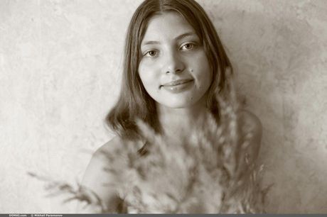 Winsome teen Ylia models totally naked in a field of tall grasses
