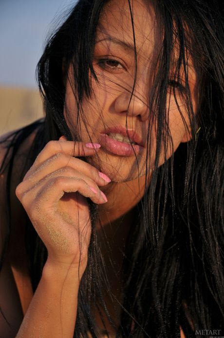 Dark haired beauty Diva A models naked on a rocky beach in heels