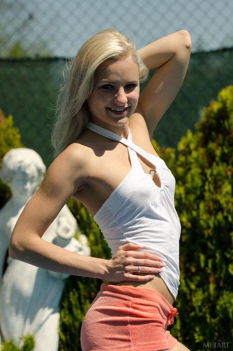 Blonde teen Claudie A strips down while in a backyard pool