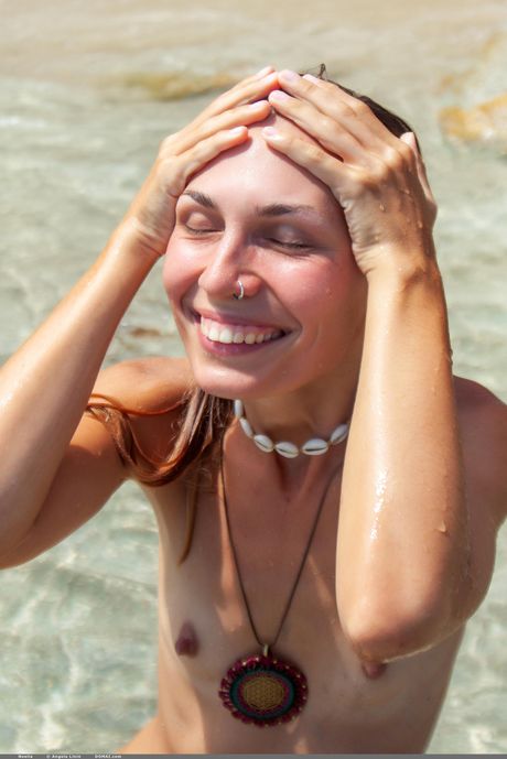 Die junge Brünette Noelia entblößt ihren Körper alleine an einem Sandstrand
