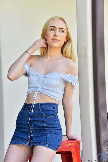 Ligh-haired teen Candy White removes a skirt before fingering her pussy outdoors