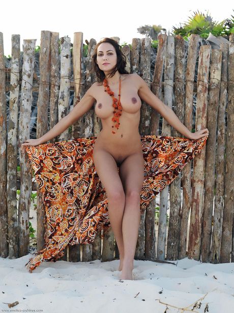 Redheaded babe Gabriela strips and poses naked on the beach