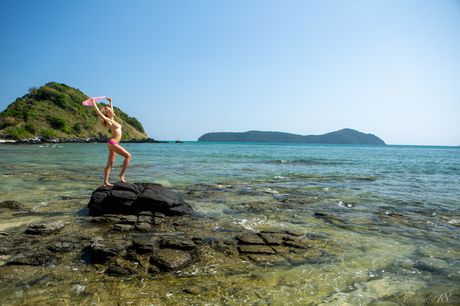 Sexig ryska Belle Delilah G poserar naken på en stenig utbrott vid sjön
