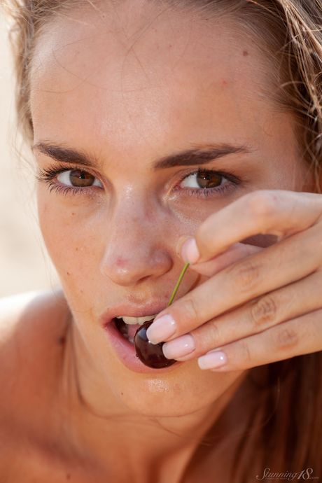 Dejlig teenager Milana F går nøgen på en sandstrand i vandet
