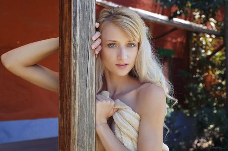 Blonde teen Nika N strikes great nude poses on a patio in the shade