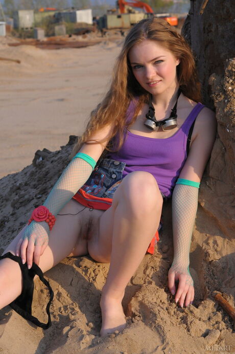 Lean teen Bridgit A gets naked in the sand and poses in the water