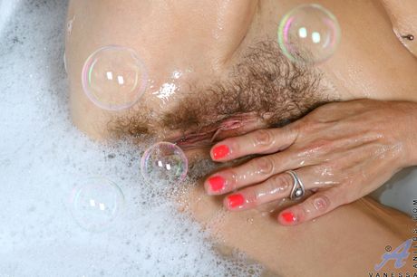 Blonde mature Vanessa masturbates with a black toy in a bathtub