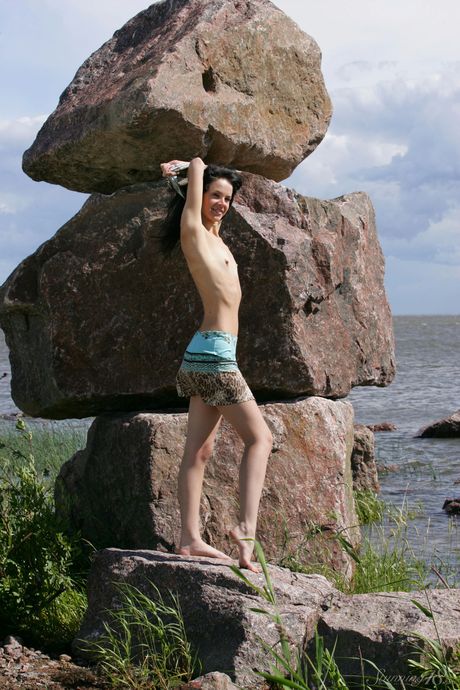 Slender teen Anais gets naked on a rocky outcropping in the water