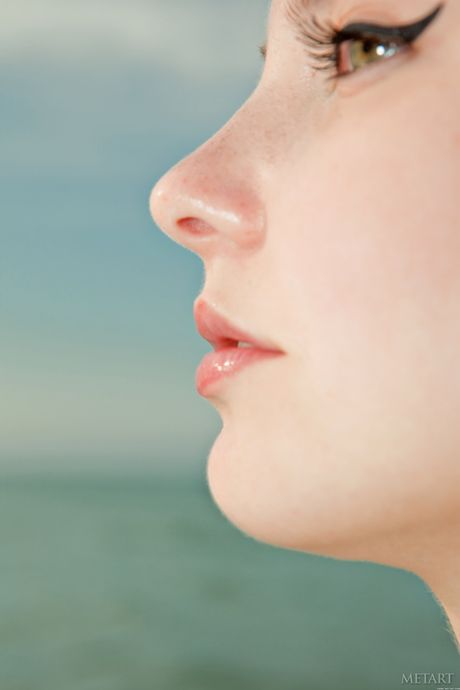 Naked Russian girl Nalli A shows her big tits and bald pussy on a beach