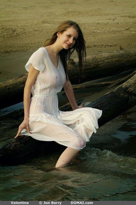 Adolescente delgada Valentina se desnuda en una playa de arena y en el agua
