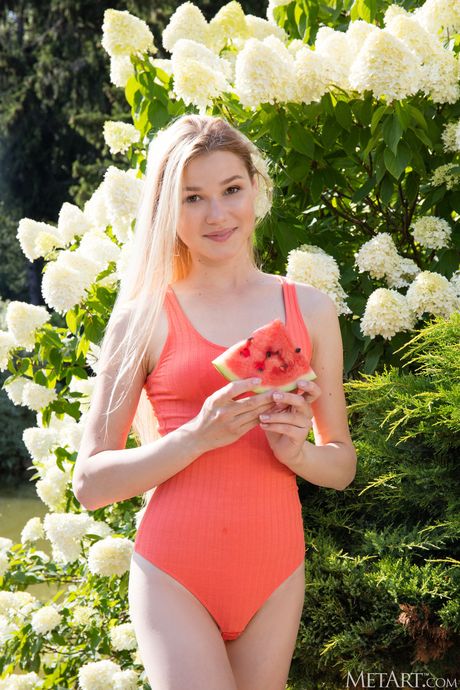 Slim teen Celestine removes a swimsuit to pose nude in a garden