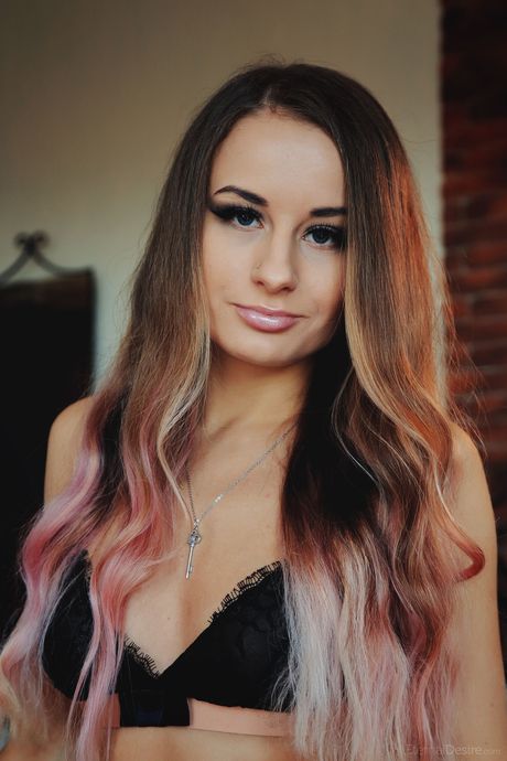 Young redhead Lili F removes a bra and panty set to get naked on a bed