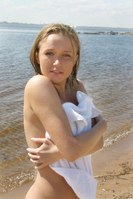 Blonde teen Sonya A bares her body on a beach towel in the nude