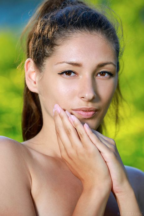 Sexy teen Rosella goes naked in a garden while holding a flower