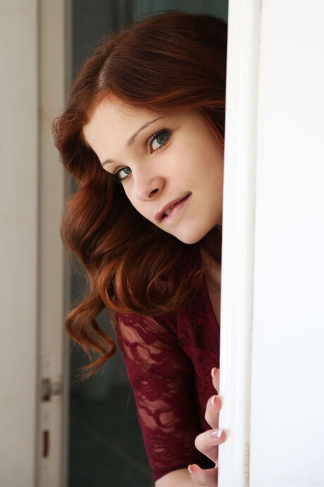 Redheaded teen Emanuelle fingers her pussy after getting naked on a bed