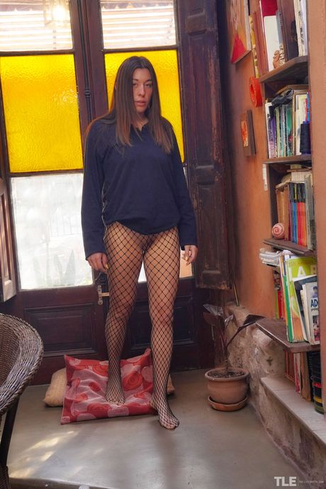 Engaging teen Angie R strips to black mesh pantyhose before a finger fuck