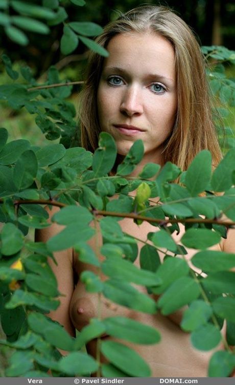 Naturalna blondynka Vera pozuje nago w lesie z długowłosym kotem
