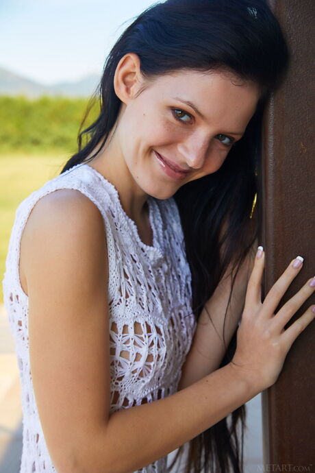 Beautiful teen Anie Darling removes a crocheted dress to pose nude in a field