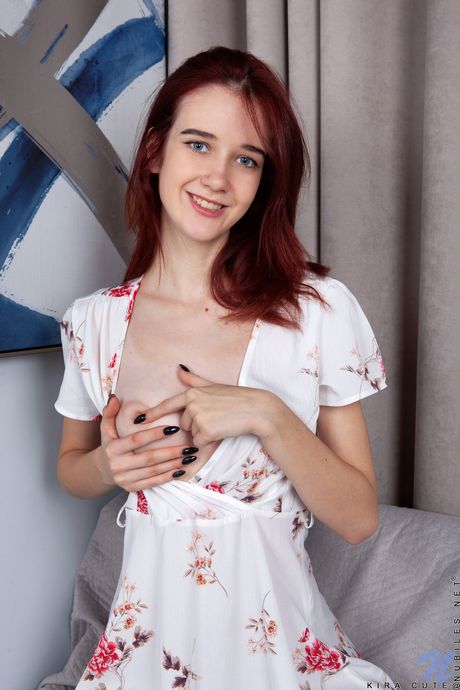 Sexy redhead Kira Cute removes a dress and heels to model in the nude