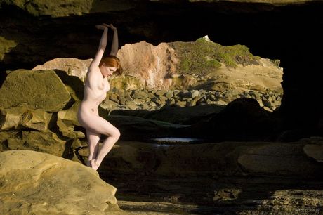 Natural redhead Ginger R displays her naked body on a rocky beach