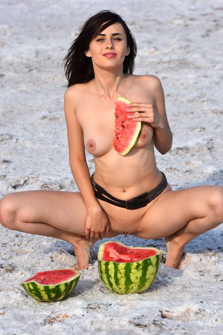 Pretty teen Mona poses nude on the beach with a watermelon in her hands