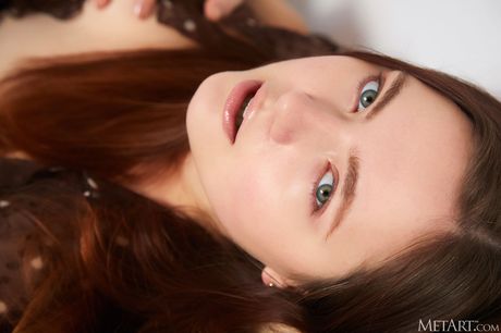 Sexy redhead Candy Kate removes her shirt to model naked with allure