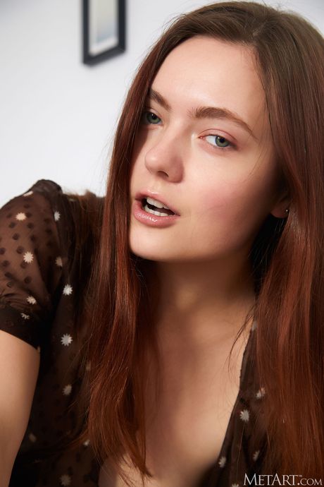 Sexy redhead Candy Kate removes her shirt to model naked with allure