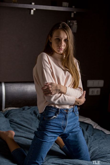 Teen girl Mirabella removes her jeans before playing with her pussy on a bed