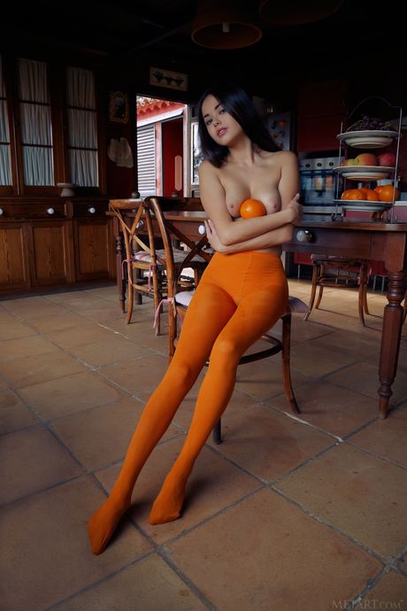 Sexy brunette Li Moon eats grapes while posing in orange stockings