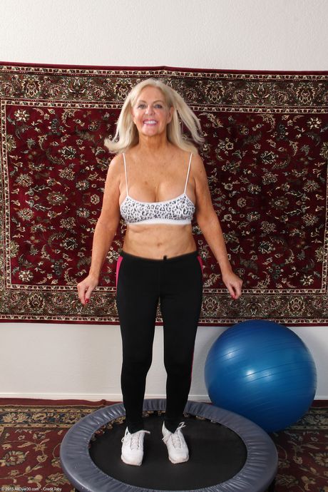 Reife blonde Judy Mayflower zeigt ihre großen Titten und verbreitet ihre Twat auf einem Trampolin
