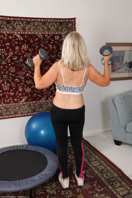 Mature blonde Judy Mayflower shows her big tits and spreads her twat on a trampoline