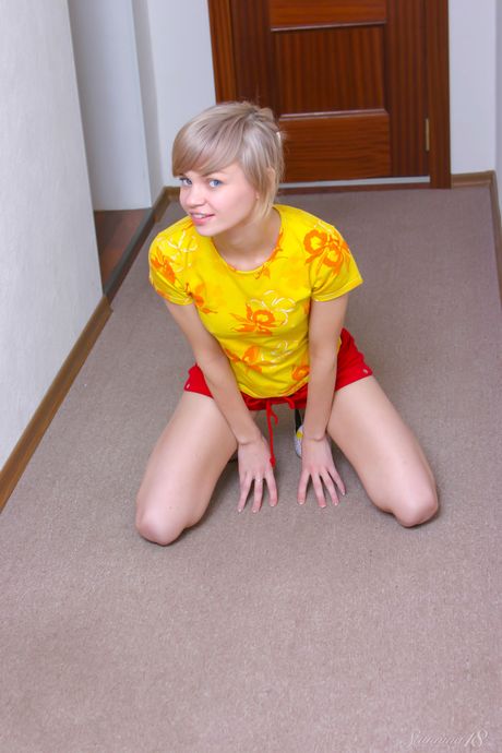 年轻的金发女郎 Macarena J 在走廊里穿着一双袜子赤身裸体
