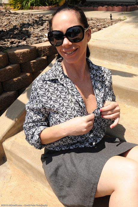 Mature secretary Kira I strips and shows her big tits and hot ass