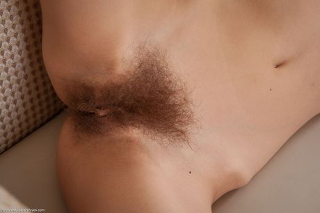 Young redhead Dennie removes a bra and panty set to pose nude